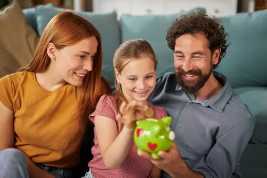Parents and child adding coins to piggybank
