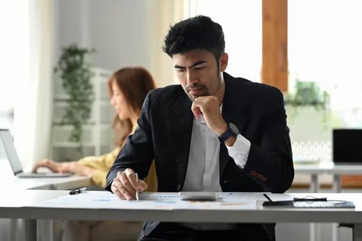 Person reviewing paperwork at a desk in an office